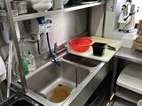 stainless steel shelvings in a kitchen with a sink and a trash can