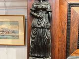 a statue of a woman holding a book on top of a shelf