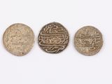 three silver coins with arabic writing on them sitting next to each other