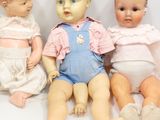 three baby dolls sitting next to each other on a white surface