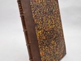 un vieux livre à la couverture brune posé sur une surface blanche
