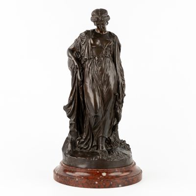une statue en bronze représentant une femme tenant un enfant dans ses bras, posée sur un socle en marbre