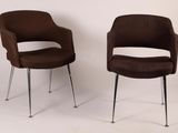 two brown chairs sitting next to each other on a white surface