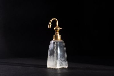a small glass bottle with a brass handle on a black surface