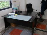 un bureau noir avec un plateau en verre et une chaise noire