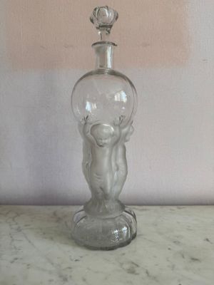 une bouteille en verre transparent contenant un bébé, posée sur une table