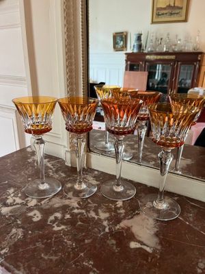 five wine glasses sitting on a counter with a mirror in the background