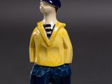 a small figurine of a man wearing a yellow shirt and blue pants