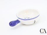 a small white bowl with a blue handle on a white surface