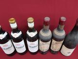several bottles of wine are lined up on a red cloth