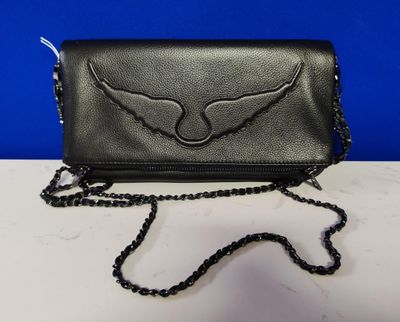 black leather purse with winged wings on it on a white table