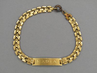 un gros plan d'un bracelet en or orné d'une plaque portant un nom