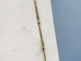 collier plaqué or orné de perles de verre vertes sur un fond de marbre blanc