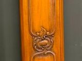 une grande horloge de parquet en bois, surmontée d'un vitrail