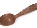 an old wooden spoon with a carved handle on a white surface