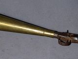 un cornet en laiton en forme de pistolet posé sur une table
