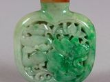 a green glass bottle with a carved design on it