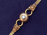 a close up of a gold bracelet with a skull on it