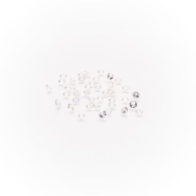 white and clear crystal beads scattered on a white surface