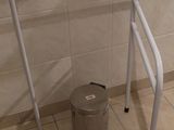 des toilettes avec un cadre métallique, à côté d'une poubelle