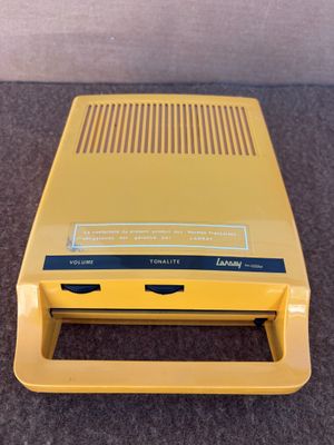 une vieille console Nintendo jaune posée sur un sol recouvert de moquette