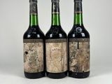 trois bouteilles de vin posées les unes à côté des autres sur une surface blanche