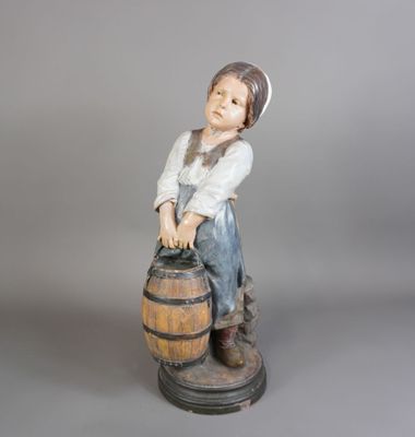 figurine représentant un garçon assis sur un tonneau, coiffé d'un chapeau