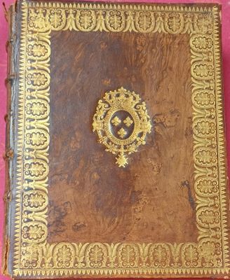 un vieux livre aux tranches dorées et orné d'un médaillon sur la couverture