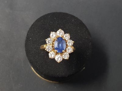 un gros plan d'une bague en or sertie d'une pierre bleue entourée de diamants blancs