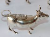 a lot of silver cow figurines sitting on a table