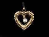 a gold heart pendant with a pearl in the center