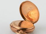 a gold pocket watch sitting on a white surface