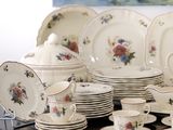 many plates and cups on a table with a painting in the background