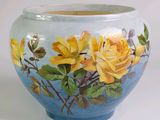un vase bleu sur lequel sont peintes des roses jaunes