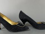 a pair of black shoes with a gold buckle on the heel