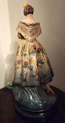 une photo représentant une figurine de femme en robe posée sur une table