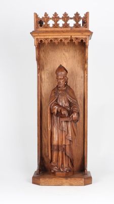 carved wooden statue of a man holding a book in his hands