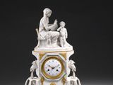 une horloge blanche et dorée surmontée d'une statue