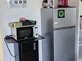 a kitchen with a refrigerator, microwave, and a shelf in it