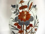 a white vase with a red and blue flower design on it