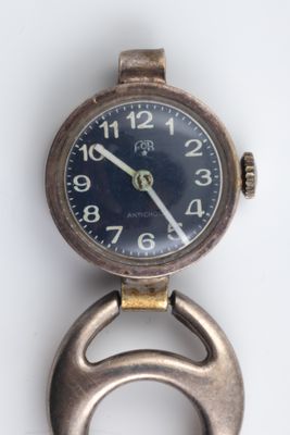 a watch with a bottle opener on it on a white surface