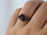 a woman ' s hand holding a ring with three different colored stones