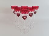 six verres à vin rouges alignés sur une surface blanche