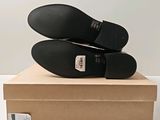 pair of black shoes sitting on top of a box on a white surface