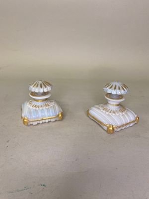 Deux figurines blanches et dorées sont posées sur une table