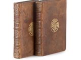 an old book with a gold medallion on the front and a brown book on the back