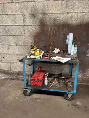 un chariot de chantier bleu chargé d'outils, devant un mur de briques