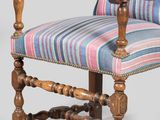 an old wooden chair with a striped upholstered seat