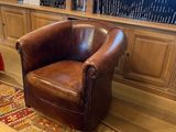 un fauteuil en cuir marron placé devant une bibliothèque