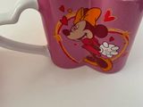 a cup with a mickey mouse design on it next to a cup with a mickey mouse design on it